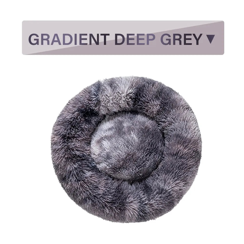 Fluffy donut-shaped dog bed in long plush material, shown in a light grey colour with a raised edge.