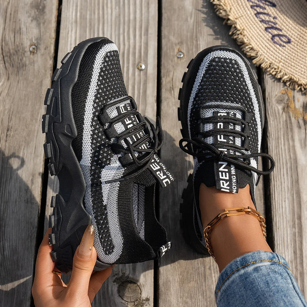 Women's Flyknit mesh lace-up sneakers in a grey colourway on a flat rubber sole.