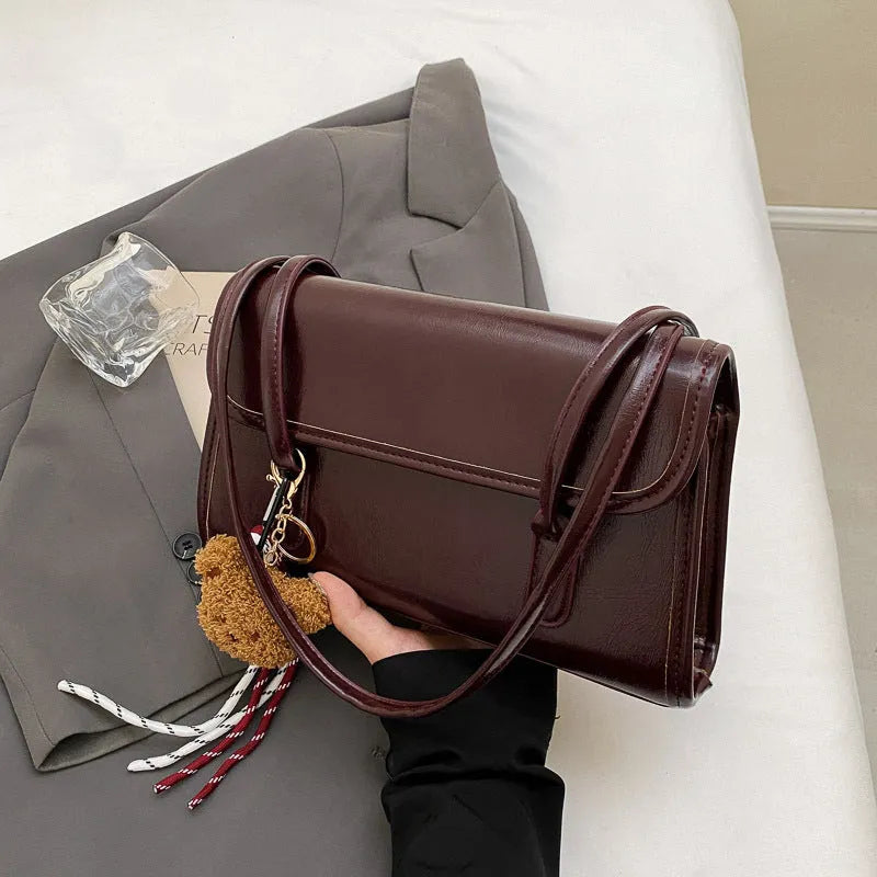 Brown women's PU leather shoulder bag with square shape, pendant detail, and double shoulder straps