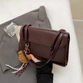 Brown women's PU leather shoulder bag with square shape, pendant detail, and double shoulder straps