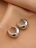 Nine pairs of smooth geometric hollow stud earrings in gold and silver finishes on a white surface