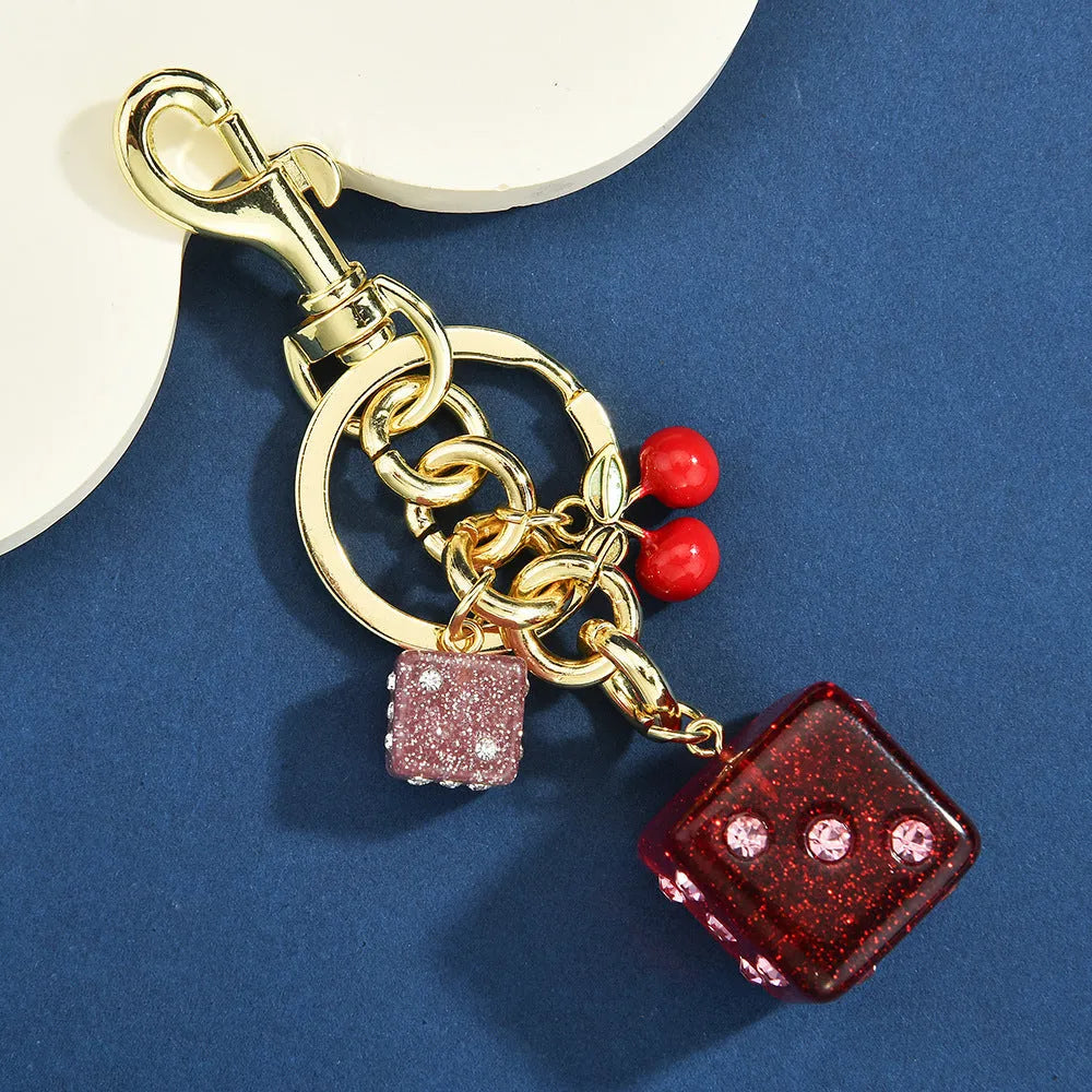 Vintage cherry red two-tone dice pendant on a metal keychain, a retro suitcase ornament.