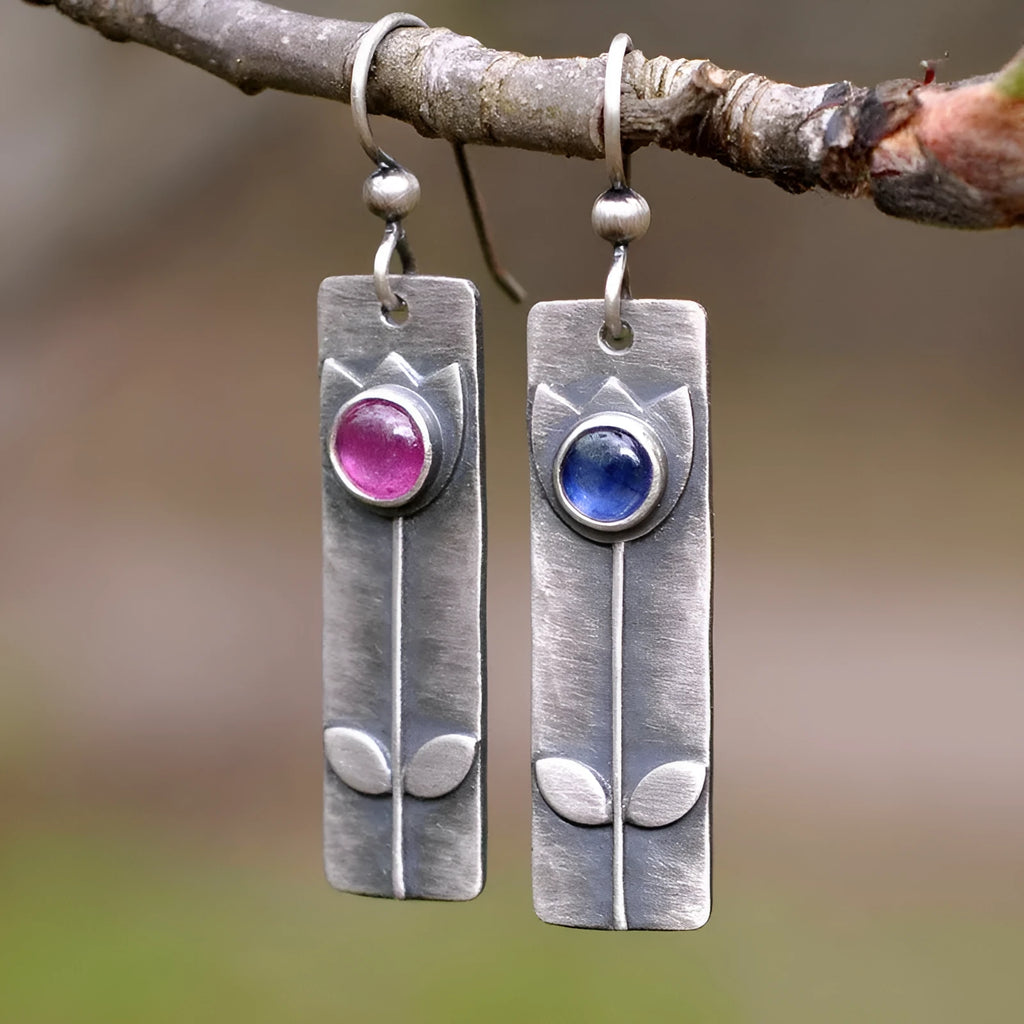 A pair of red sapphire earrings with an antique finish and geometric elliptical shape.