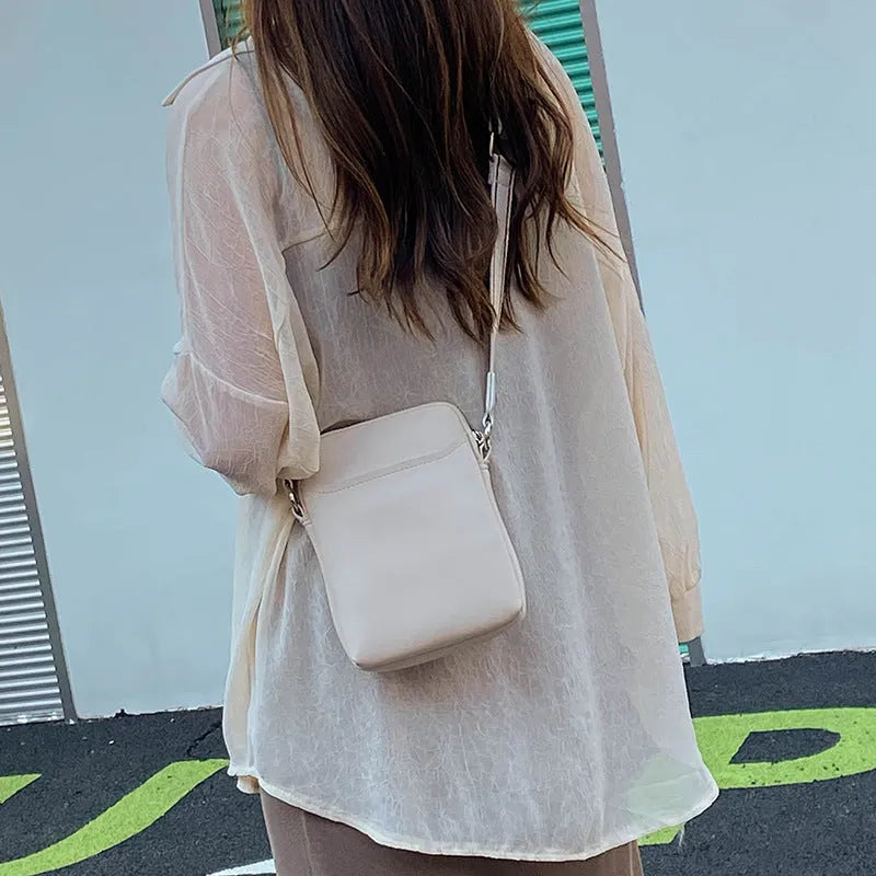 Solid colour small crossbody mobile phone bag in beige, showing front view and adjustable strap.