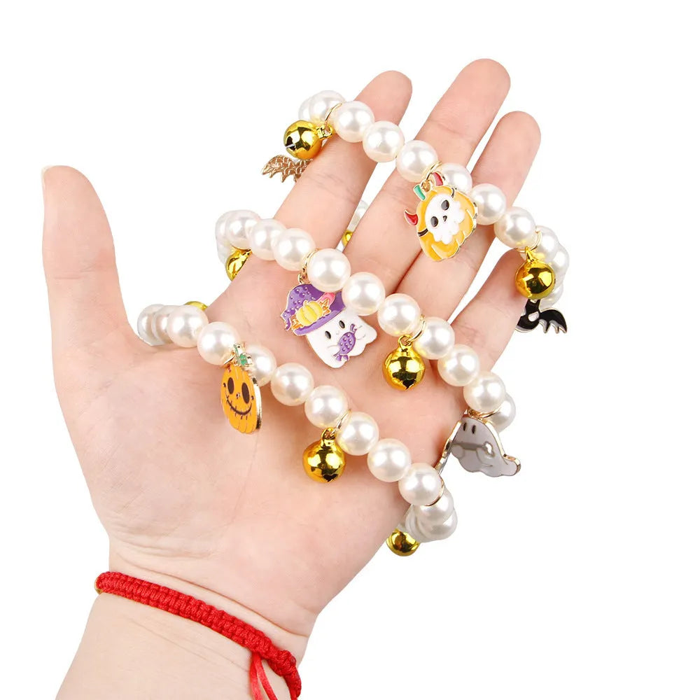 Adjustable simulated pearl necklace cat collar with a Halloween pumpkin charm in purple ghost, skull, or smile designs.