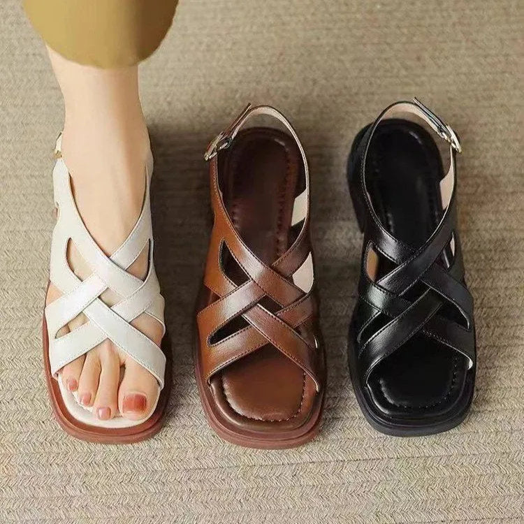 Women's black patent leather low heel sandals with square toe and cross ankle strap.