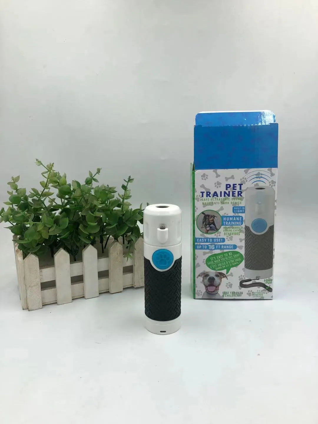 White handheld ultrasonic dog bark stop trainer on a plain background.