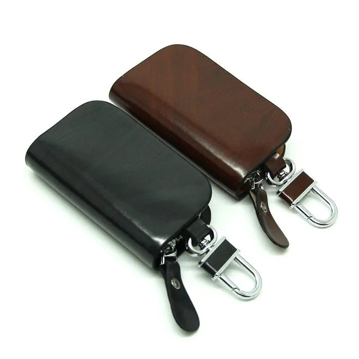 Black frosted leather car key case with zipper, next to a car key