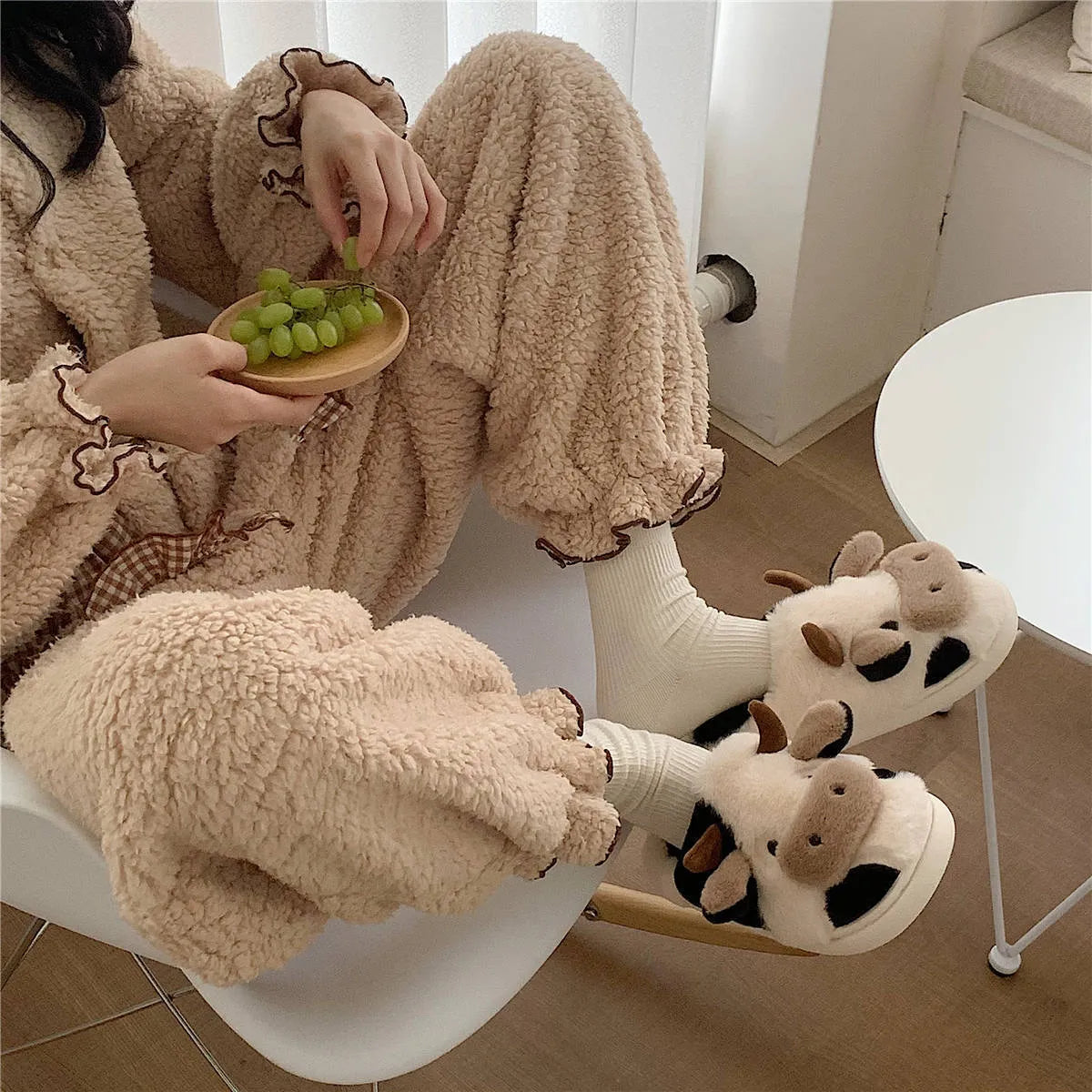White plush cow slippers for women with a non-slip textured sole.