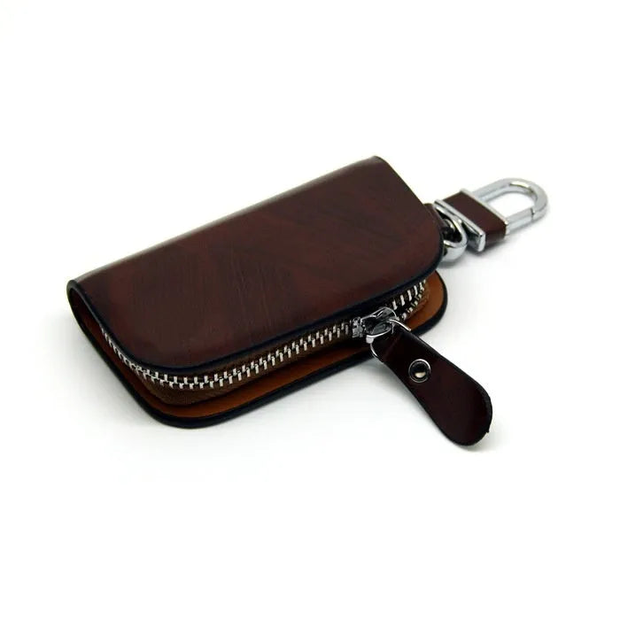 Black frosted leather car key case with zipper, next to a car key