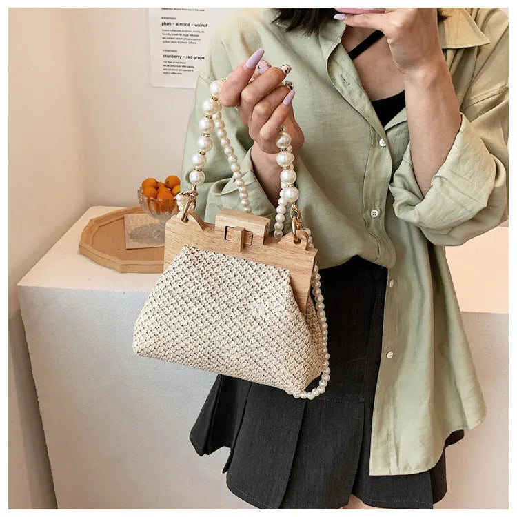 Women's straw woven shoulder bag with pearl chain detail showing internal organisation compartments