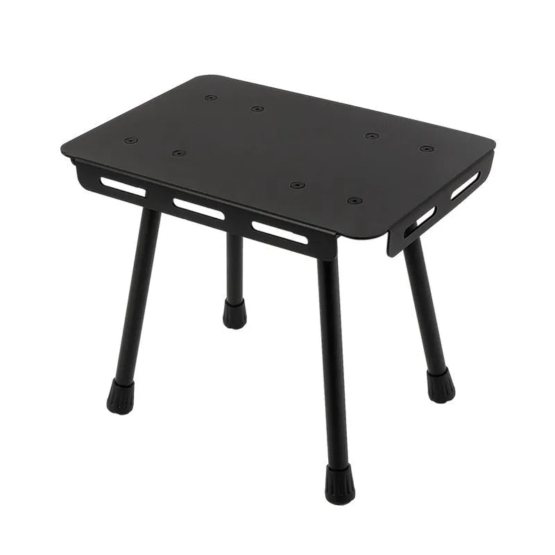 Aluminium folding camping stool that converts into a small table, shown with a tactical storage bag and a beige PU cushion.