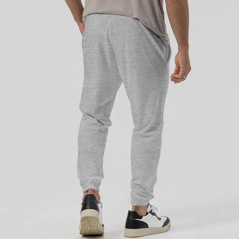 Men's grey casual track sweatpants with loose tapered cut and straight leg design, elastic waistband