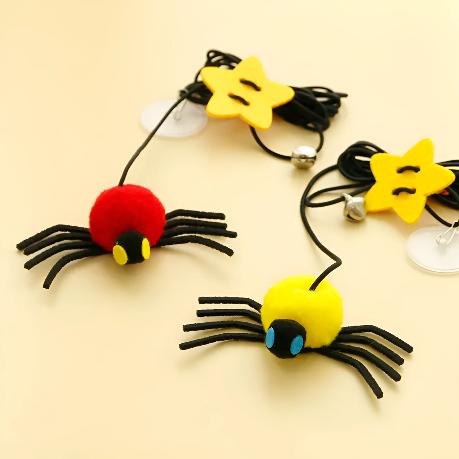 Red door hanging cat toy with elastic rope, feather, bell, and spider attachment on a white door.